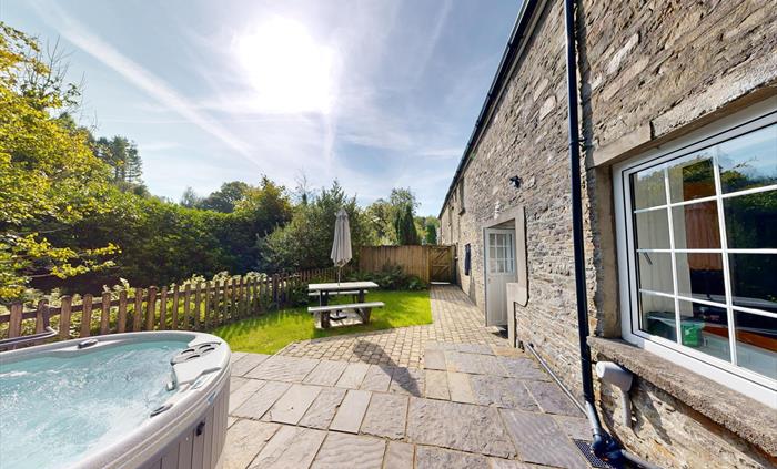 Stone terrace and enclosed garden with hot tub, picnic bench, and river views.